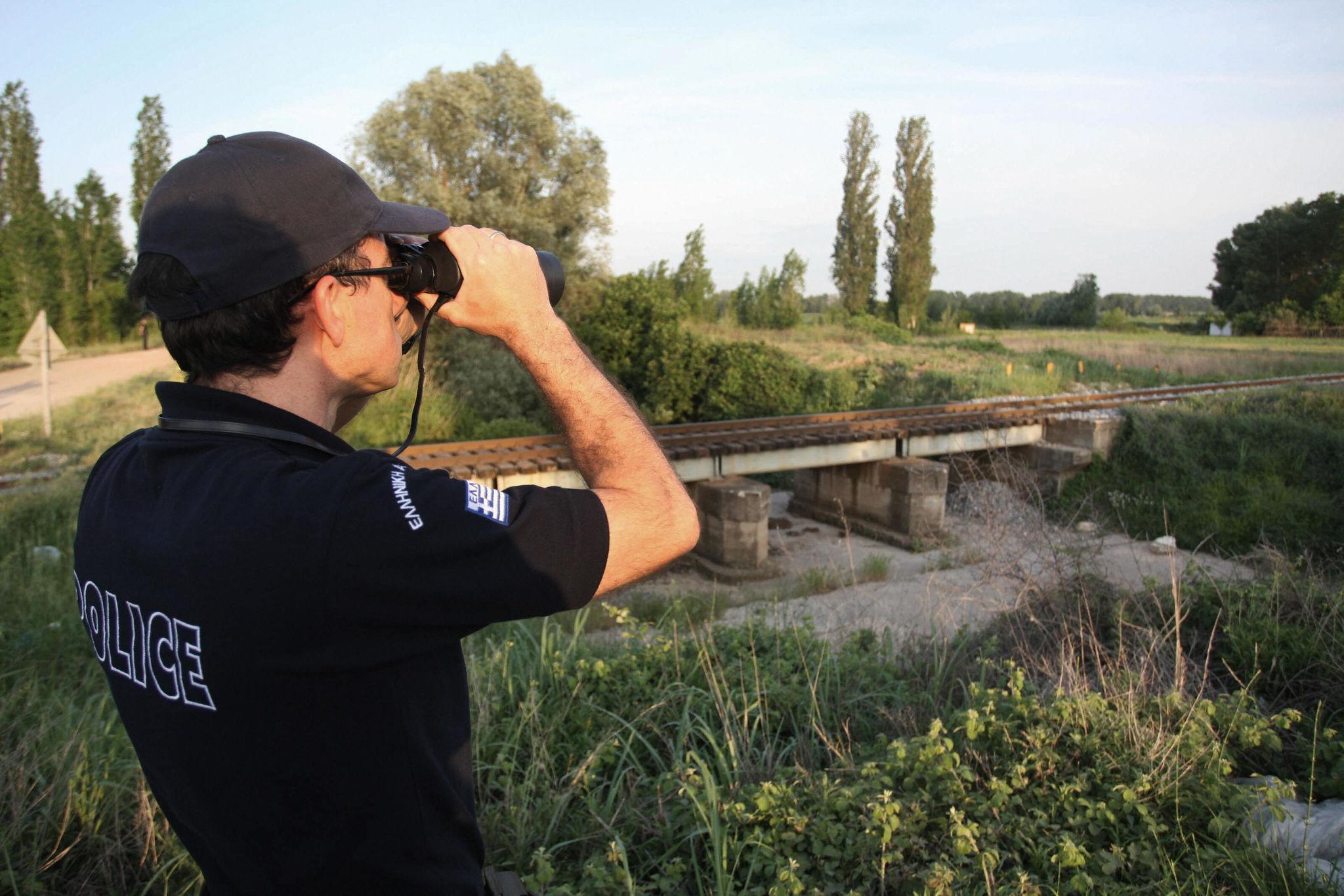 A customs officer uses binoculars to spo
